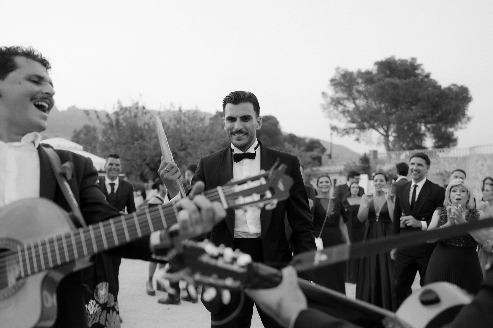 Músicos con guitarras y el novio con un abanico, al aire libre
